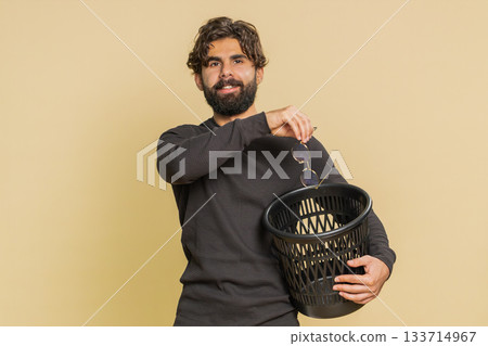 Indian young man taking off throwing out glasses into bin after laser treatment on beige background 133714967
