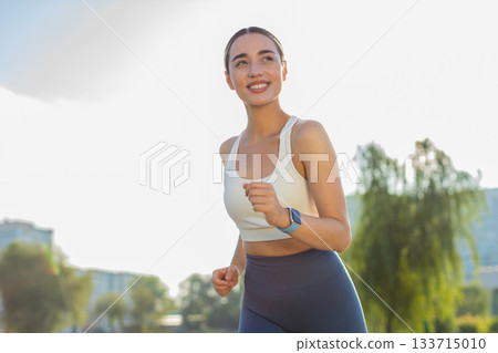 Active sportswoman jogging training marathon run in city summer sunny park Active sportswoman jogging training marathon run in city summer sunny park 133715010