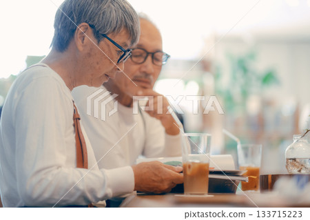 Relaxing time for senior couple enjoying magazines at cafe 133715223