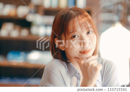 一位二十多歲的女子在咖啡館放鬆,手裡拿著一台相機。 一位二十多歲的女子在咖啡館放鬆,手裡拿著一台相機。 133715591