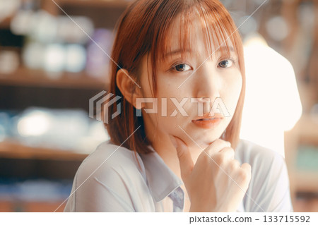 一位二十多歲的女子在咖啡館放鬆，手裡拿著一台相機。 133715592