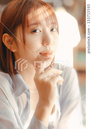 一位二十多歲的女子在咖啡館放鬆，手裡拿著一台相機。 133715593