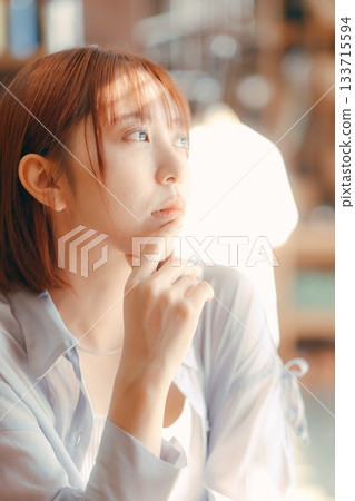 一位二十多歲的女子在咖啡館放鬆,手裡拿著一台相機。 一位二十多歲的女子在咖啡館放鬆,手裡拿著一台相機。 133715594