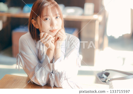 一位二十多歲的女子在咖啡館放鬆,手裡拿著一台相機。 一位二十多歲的女子在咖啡館放鬆,手裡拿著一台相機。 133715597