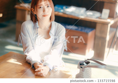 一位二十多歲的女子在咖啡館放鬆,手裡拿著一台相機。 一位二十多歲的女子在咖啡館放鬆,手裡拿著一台相機。 133715598