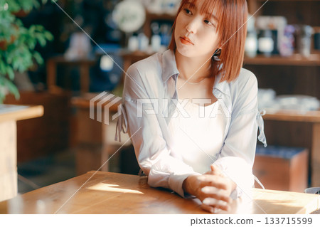 A woman in her 20s relaxing at a cafe with a camera 133715599