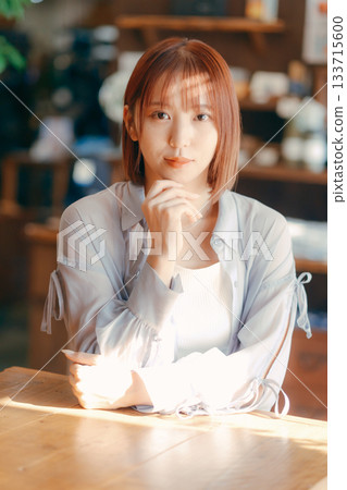A woman in her 20s relaxing at a cafe with a camera A woman in her 20s relaxing at a cafe with a camera 133715600