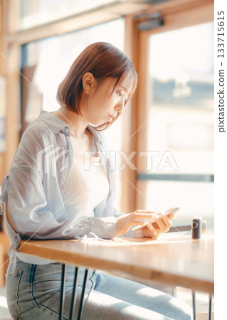 A woman in her 20s relaxing at a cafe with a camera A woman in her 20s relaxing at a cafe with a camera 133715615