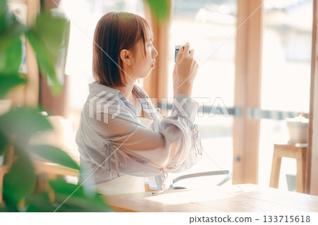 A woman in her 20s relaxing at a cafe with a camera A woman in her 20s relaxing at a cafe with a camera 133715618