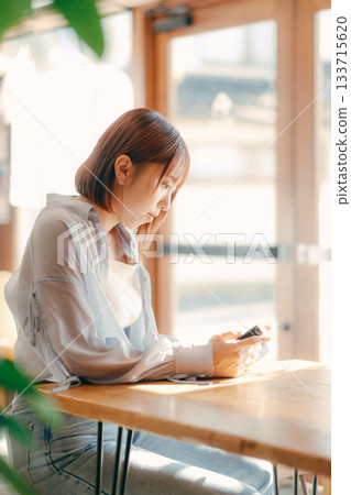 A woman in her 20s relaxing at a cafe with a camera 133715620