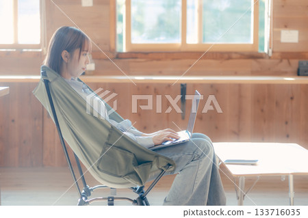 一位二十多歲的女性舒適地坐在椅子上,這是她工作時的場景。 一位二十多歲的女性舒適地坐在椅子上,這是她工作時的場景。 133716035