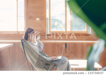 A work scene of a woman in her twenties sitting comfortably in a chair 133716037