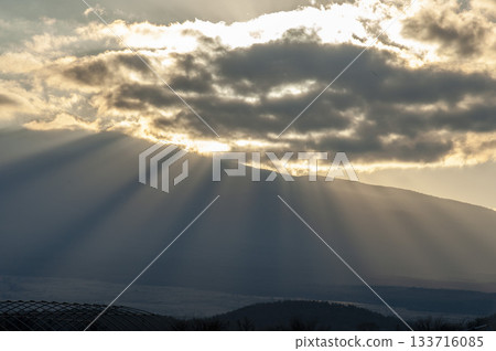 富士山脊上，夕陽的雲層中透出縷縷光芒，映照著忍野村的景色。 133716085