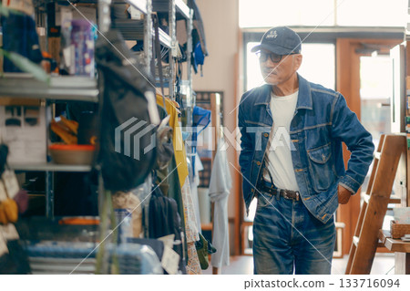A typical scene of a man in his 60s picking up a magazine in a store 133716094
