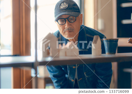 一個六十多歲的男人在商店裡拿起一本雜誌的典型場景 一個六十多歲的男人在商店裡拿起一本雜誌的典型場景 133716099