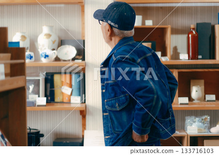 A typical scene of a man in his 60s picking up a magazine in a store A typical scene of a man in his 60s picking up a magazine in a store 133716103