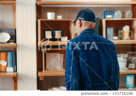 A typical scene of a man in his 60s picking up a magazine in a store 133716106