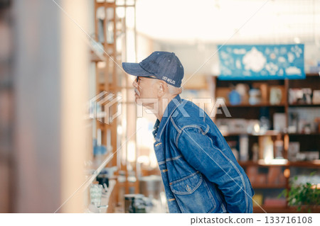 一個六十多歲的男人在商店裡拿起一本雜誌的典型場景 一個六十多歲的男人在商店裡拿起一本雜誌的典型場景 133716108