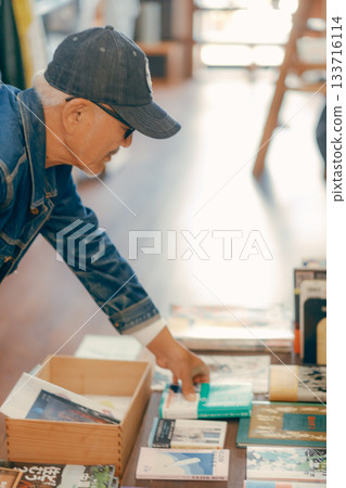 一個六十多歲的男人在商店裡拿起一本雜誌的典型場景 一個六十多歲的男人在商店裡拿起一本雜誌的典型場景 133716114