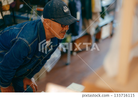 一個六十多歲的男人在商店裡拿起一本雜誌的典型場景 一個六十多歲的男人在商店裡拿起一本雜誌的典型場景 133716115