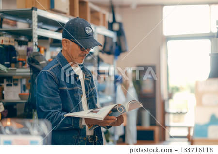 A typical scene of a man in his 60s picking up a magazine in a store 133716118