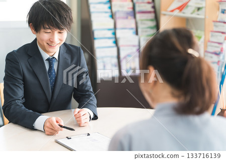 Young Asian businessman negotiating with a female customer (car/insurance) Young Asian businessman negotiating with a female customer (car/insurance) 133716139