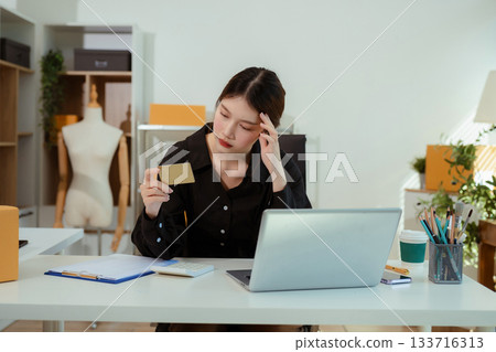 stressed and headache-ridden woman dealing with online sales losses. 133716313