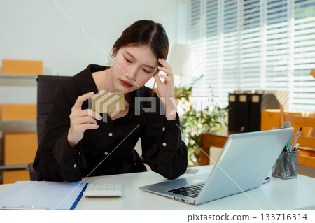 stressed and headache-ridden woman dealing with online sales losses. 133716314