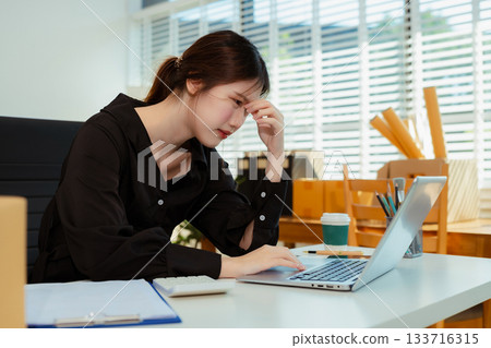 stressed and headache-ridden woman dealing with online sales losses. 133716315
