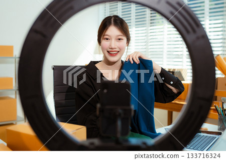 Asian vlogger woman influencer, SME retail store owner smile enjoy selling show live sale online screen smartphone. 133716324