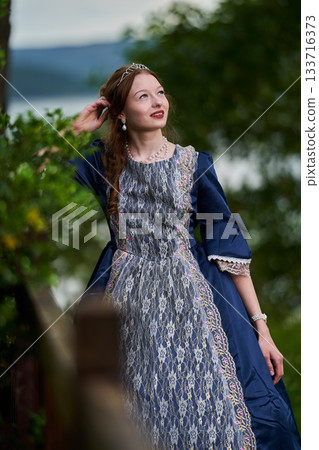 Portrait of a young redhead girl in Victorian style dress posing beside castle Portrait of a young redhead girl in Victorian style dress posing beside castle 133716373