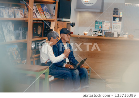 一對老年夫婦在咖啡館使用電腦和智慧型手機進行研究的場景 133716399