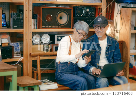 一對老年夫婦在咖啡館使用電腦和智慧型手機進行研究的場景 133716403