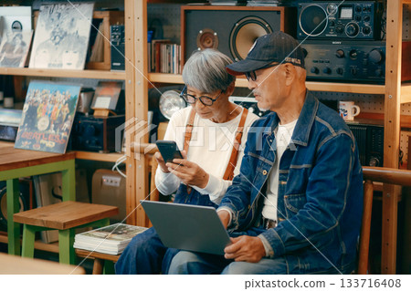 A scene where a senior couple uses a computer and smartphone to do research in a cafe 133716408