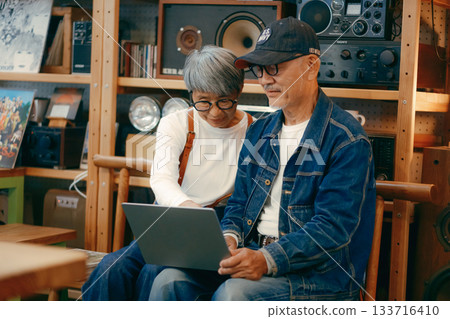 一對老年夫婦在咖啡館使用電腦和智慧型手機進行研究的場景 一對老年夫婦在咖啡館使用電腦和智慧型手機進行研究的場景 133716410
