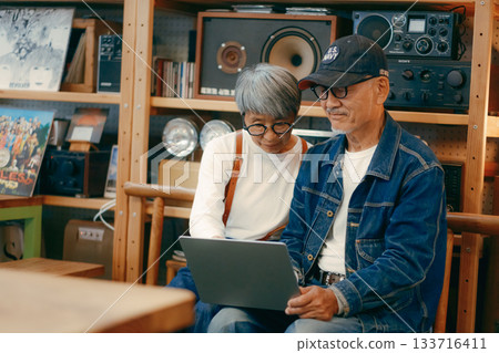 A scene where a senior couple uses a computer and smartphone to do research in a cafe A scene where a senior couple uses a computer and smartphone to do research in a cafe 133716411