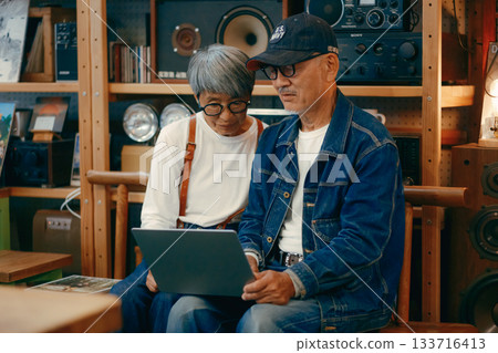 A scene where a senior couple uses a computer and smartphone to do research in a cafe 133716413