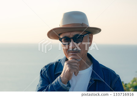 Portrait of a senior man looking out at the sea at sunset Portrait of a senior man looking out at the sea at sunset 133716916