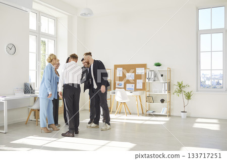 Business people putting their arms together in a stack standing in a circle in modern office Business people putting their arms together in a stack standing in a circle in modern office 133717251