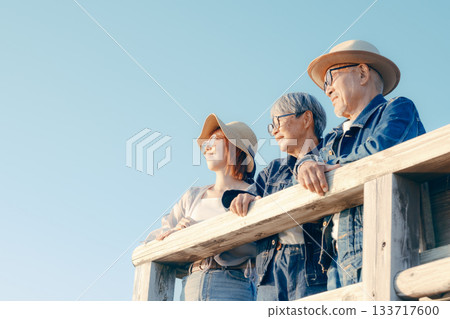黃昏時分，一對父母和孩子一起眺望大海的景象 133717600