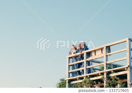 黃昏時分，一對父母和孩子一起眺望大海的景象 133717605
