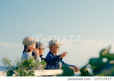 黃昏時分，一對父母和孩子一起眺望大海的景象 133717617