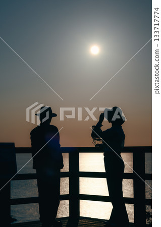 Silhouette of a parent and child watching the sunset at sea 133717774