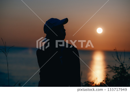 Silhouette of a young woman standing in the evening light 133717949