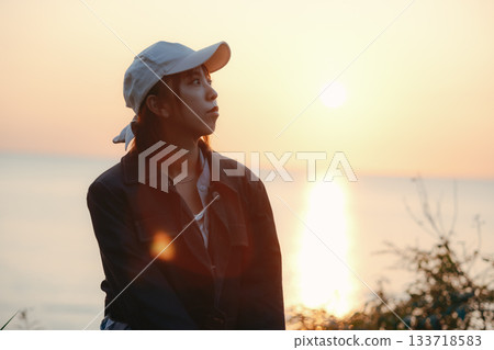 Twilight portrait of a woman gazing at the sunset 133718583