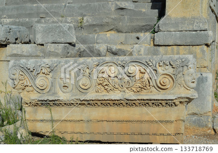 Historical stone bas-relief with carved faces in the ancient city of Myra, Demre, Antalya Province, Lycia, Turkey. 133718769