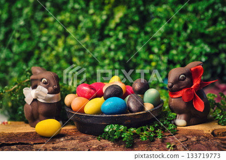Chocolate Easter eggs with rabbit and egg candies on a wooden table in the yard Chocolate Easter eggs with rabbit and egg candies on a wooden table in the yard 133719773