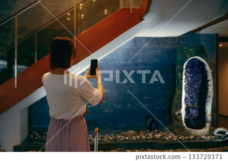 A woman in her 20s taking a photo in a hotel lobby A woman in her 20s taking a photo in a hotel lobby 133720371