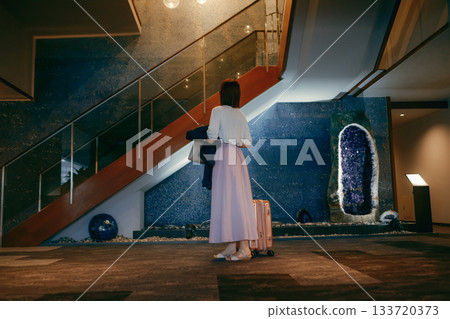 A woman in her 20s taking a photo in a hotel lobby 133720373