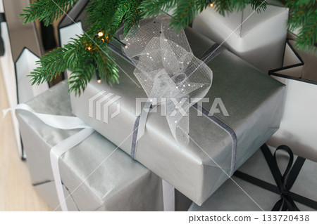 Christmas gift boxes wrapped with silver paper and elegant ribbons under festive tree lights Christmas gift boxes wrapped with silver paper and elegant ribbons under festive tree lights 133720438